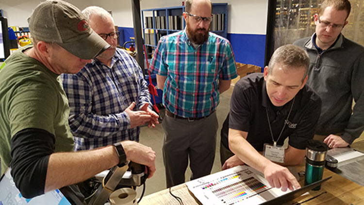 Hub Labels and Nazdar consultants review test prints and color curve data. 